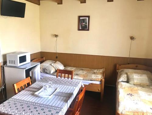 a room with two beds and two tables and a microwave at Convoy Panzió in Szajol