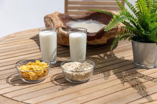 a table with three glasses of milk and bowls of food at Krina Mare Boutique Hotel in Naxos Chora