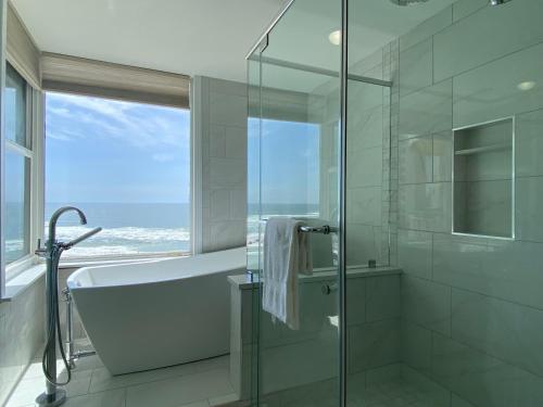 een badkamer met een douche en een bad en een raam bij Beach Colony Tower 7a By Pkrm in Pensacola