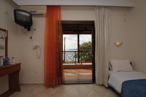 a bedroom with a bed and a television and a balcony at Panorama Spa Hotel in Ouranoupoli