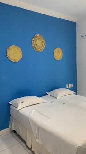 two beds in a room with a blue wall at Pousada Costa do Calhau in São Luís