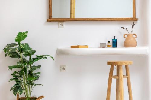 a bathroom with a mirror and a plant and a stool at Krina Mare Boutique Hotel in Naxos Chora