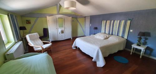 um quarto com uma cama e uma cadeira em La pinsonnière em Heiltz-le-Hutier