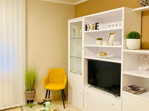 salon z telewizorem i żółtym krzesłem w obiekcie Lovely New Home w Grenadzie
