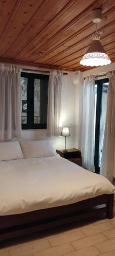 a bedroom with a large bed with white curtains at Kristi's Homes - "Beautiful Home" in Dimitsana in Dhimitsana