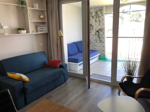 a living room with a blue couch and a sliding glass door at Très bel appartement vue mer avec piscine in Douarnenez