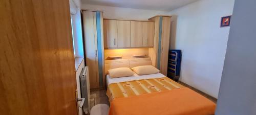 a small bedroom with an orange bed and cabinets at Guest House Barba in Bibinje