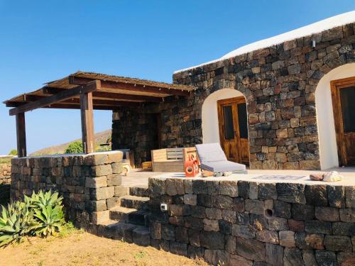 a stone house with a chair in front of it at Dammuso Ma.Vi in Pantelleria