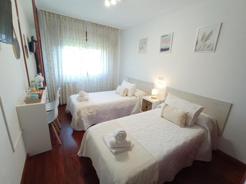 a hotel room with two beds and a window at Martínez Rooms Pilgrims in Caldas de Reis