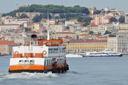 un ferry en el agua frente a una ciudad en Almada Cristo Rei en Almada