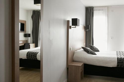 Habitación de hotel con 2 camas y espejo en Tulip Inn Massy Palaiseau - Residence, en Palaiseau
