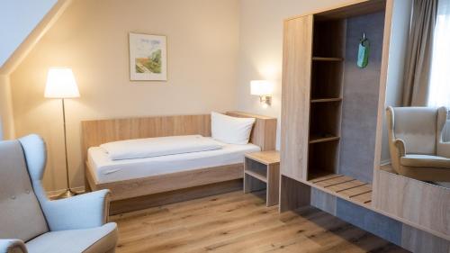 ein kleines Zimmer mit einem Bett und einem Stuhl in der Unterkunft Pension Sellent in Stendal