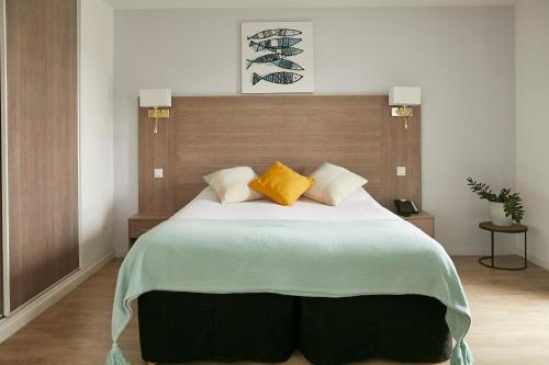 a bedroom with a large bed with two yellow pillows at Tulip Inn Massy Palaiseau - Residence in Palaiseau