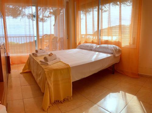 Schlafzimmer mit einem Bett mit einem Tisch und Fenstern in der Unterkunft APPARTEMENTS SOL y MAR - Cala Llevado 2 in Tossa de Mar