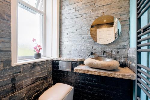 a bathroom with a sink and a mirror at Luxury Unique Townhouse with Hottub & Pizza Oven in Bolton
