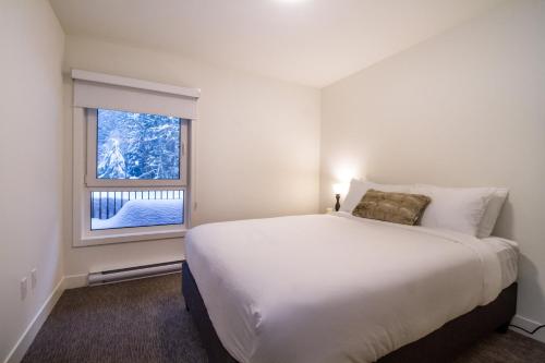 Un dormitorio con una gran cama blanca y una ventana en Magog Condo by Revelstoke Vacations, en Revelstoke