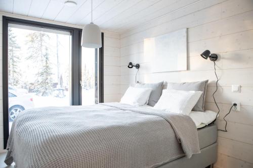 a bedroom with a bed with white sheets and a window at Villa Bruno in Syöte