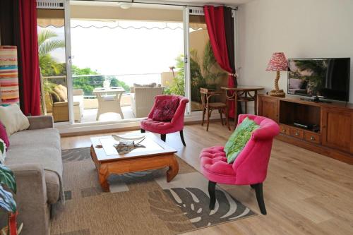 a living room with two pink chairs and a table at Très bel appartement 1 chambre vue Mer RES TAHIRI 1 in Punaauia