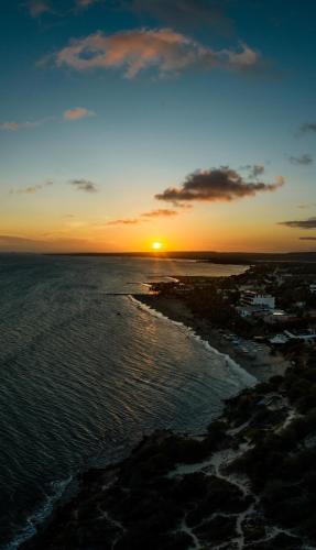 a sunset over a beach with the ocean at Hotel California Playa El Yaque in El Yaque