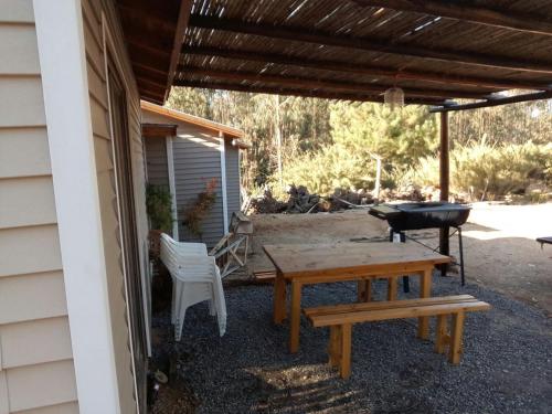 a patio with a table and a grill and a bench at Domos y Cabañas Algarrobo in Algarrobo