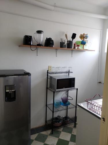eine Küche mit einer Mikrowelle und einem Regal mit Geräten in der Unterkunft Piso Macario ¡muy céntrico y bien comunicado! in Mexiko-Stadt