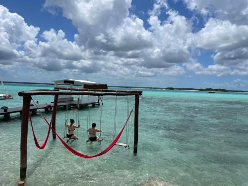 two men playing on a swing in the ocean at Hotel Aldea 19 Bacalar in Bacalar