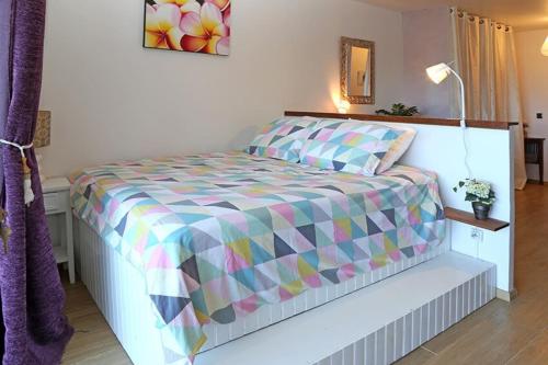 a bedroom with a bed with a colorful comforter at RESIDENCE SUNSET BEACH Studio sur la plage in Punaauia