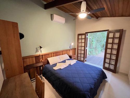 Schlafzimmer mit einem blauen Bett, einem Tisch und einem Deckenventilator in der Unterkunft Casa Tubarão - A Melhor in Camburi