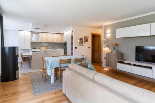 Una sala de estar y una cocina con un sofá y una mesa. en CASA BEBA - Agenzia Dolomiti Affitti, en Cavalese
