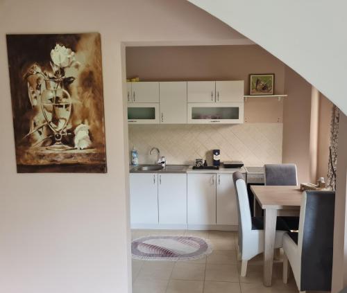 eine Küche und ein Esszimmer mit weißen Schränken und einem Tisch in der Unterkunft Apartman ALEX LUX in Vrnjačka Banja