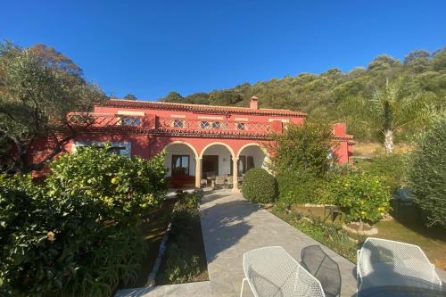 a red brick house with chairs in a garden at Finca Olivar in Gaucín
