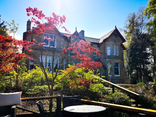 uma casa velha com uma árvore em frente em Heatherlie House Hotel em Selkirk