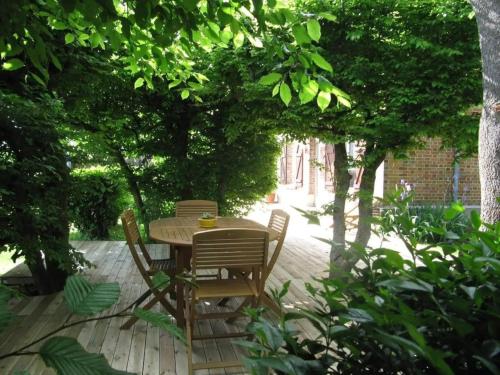 a table and chairs on a patio with trees at Le Pavillon de la mare in Avrainville