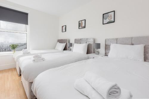2 witte bedden in een witte slaapkamer met een raam bij RST Stanley Park in Liverpool