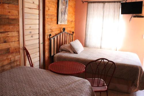 a room with two beds and a table and chairs at Cabañas Claro de Luna in Creel