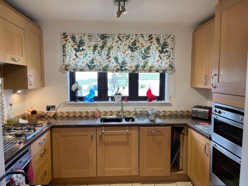 a kitchen with wooden cabinets and a sink and a window at Lindas Retreats Self catering accommodation 1 bedroom cottage or 3 bedroom House in Tomintoul