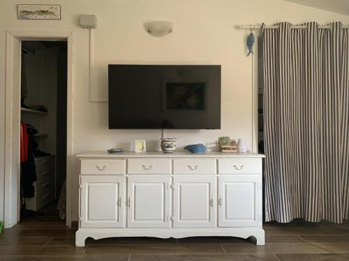 a white cabinet with a flat screen tv on a wall at Appartamento La casa di Chiara in Porto Azzurro