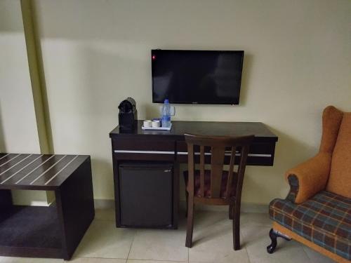 een kamer met een bureau, een televisie en een stoel bij Rendezvous hotel petra in Wadi Musa