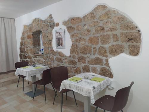 a dining room with two tables and a stone wall at B&b Le Larie in Collepardo