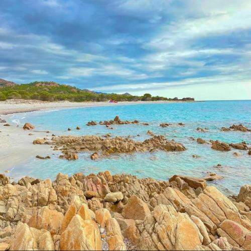 a group of rocks on a beach with blue water at MaRo Apartment in Cala Liberotto