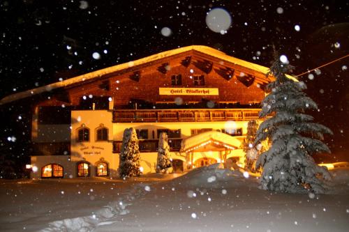 a large building with a christmas tree in the snow at Panorama-Hotel Winklerhof in Holzgau