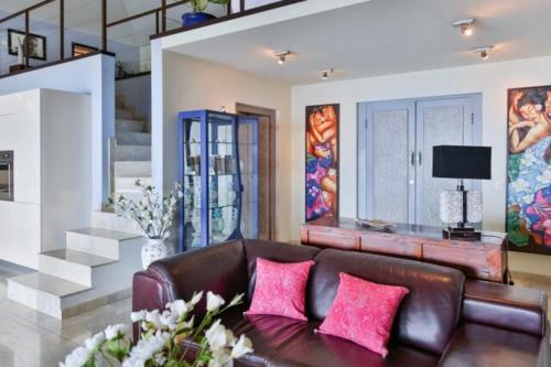 una sala de estar con un sofá de cuero marrón con almohadas rosas en Magnifique Villa Vue Mer exceptionnelle - Ireina en Punaauia