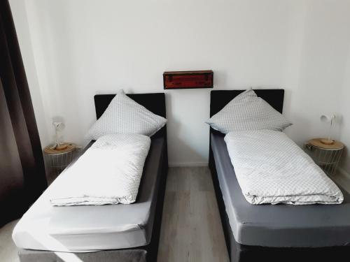 two beds in a room with white sheets and pillows at Nordunterkunft in Neumünster