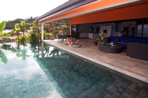 einen Pool neben einem Haus mit einem Wohnzimmer in der Unterkunft Magnifique Villa Vue Mer exceptionnelle - Ireina in Punaauia