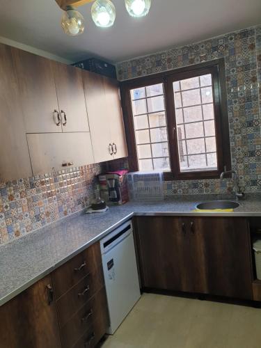 a kitchen with wooden cabinets and a window at Mardin tarihi ulu Cami yanı, Kale divan konağı in Mardin
