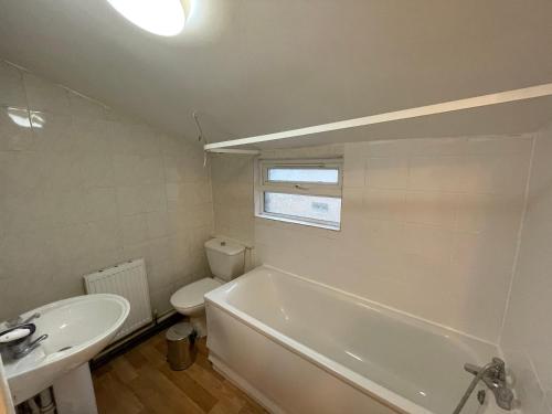 a bathroom with a tub and a toilet and a sink at 147 knapp road house in London