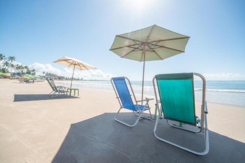 two chairs and an umbrella on the beach at Hotel Brisa Tower Maceió in Maceió