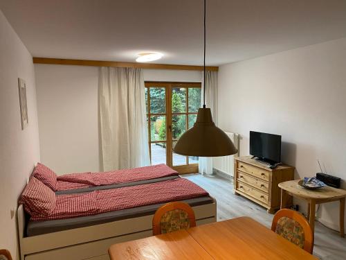 a bedroom with a bed and a table and a television at Haus Rottachbrücke May in Tegernsee