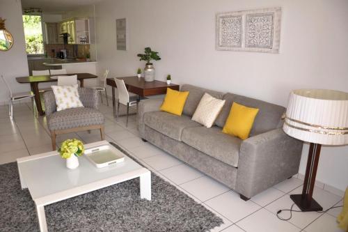 ein Wohnzimmer mit einem Sofa und einem Tisch in der Unterkunft Appartement standing 2 chambres vue mer RES TAHIRI 3 in Punaauia
