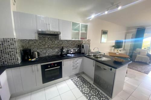 a kitchen with white cabinets and a black counter top at Grand Studio Les Horizons Papeete in Papeete
